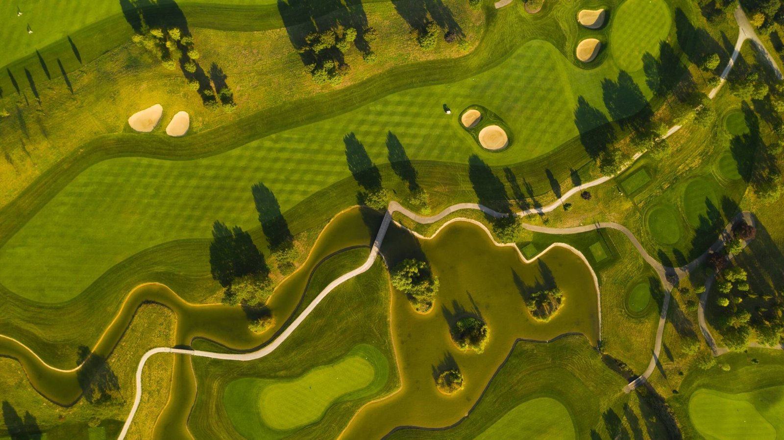 Blick von oben auf Fairways, Grüns und Wasserflächen einer Golfanlage